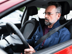 man intently looking forward, driving a car