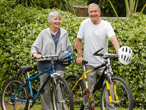 Older husband and wife with bicycles preparing for a ride.